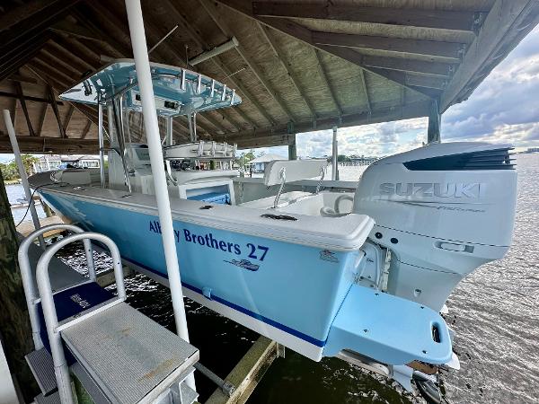 Slide: The Image of 2021 Albury Brothers 27 boat with Suzuki engine docked under a wooden shelter. - 1