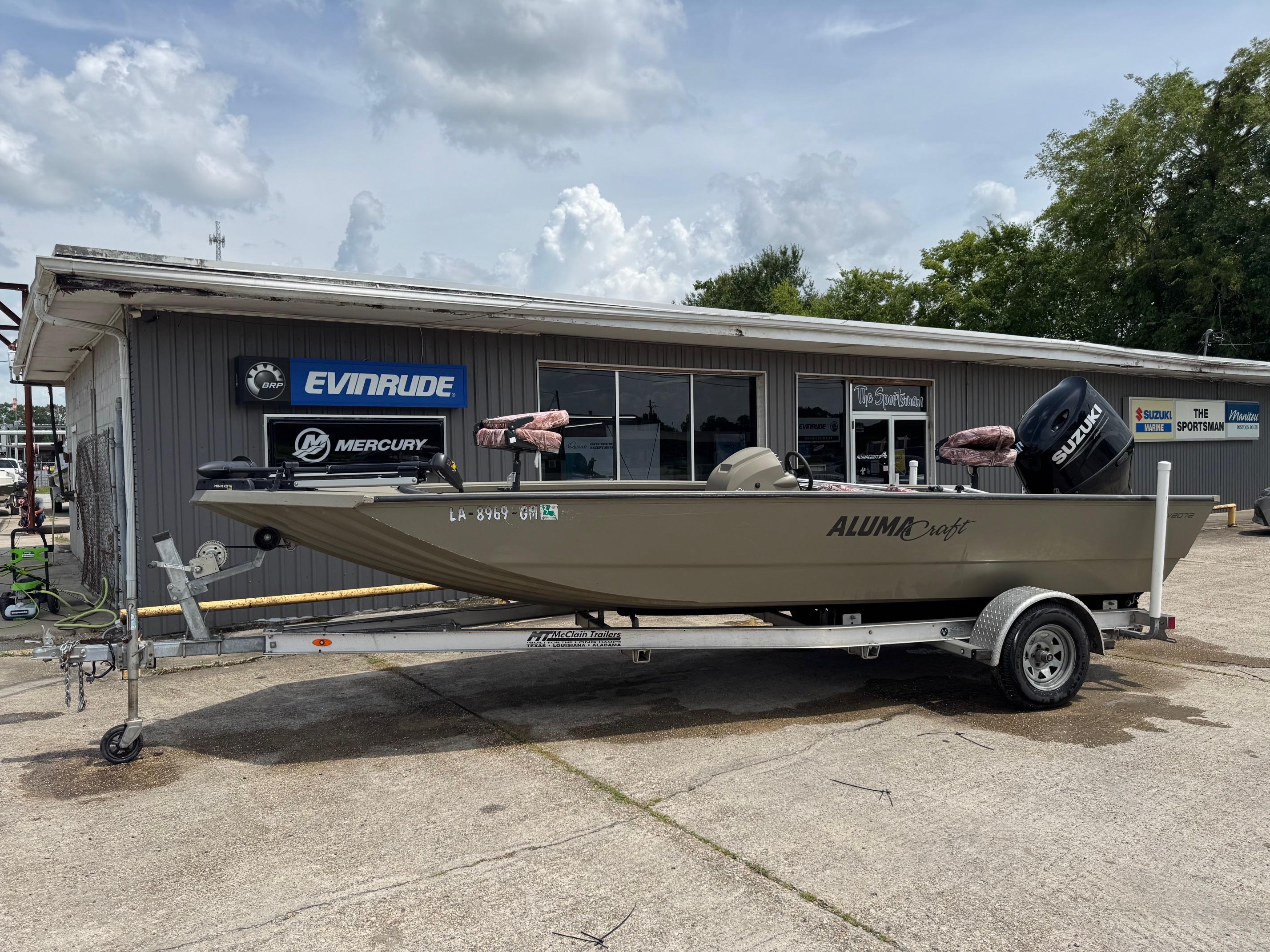 Slide: The Image of 2021 Alumacraft 2072 SC boat on trailer outside dealership, featuring Suzuki outboard motor. - 1