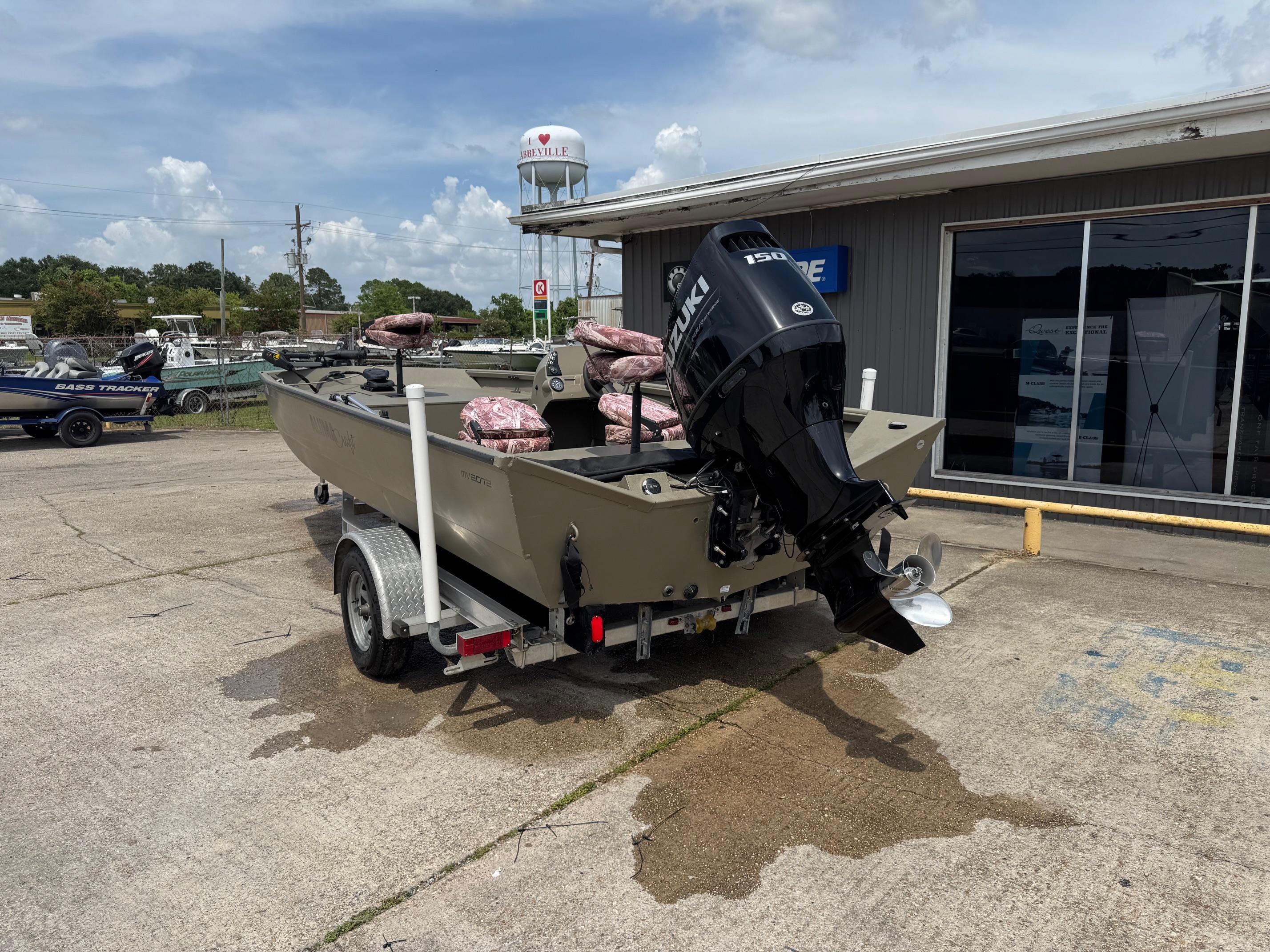 Slide: The Image of 2021 Alumacraft 2072 SC boat with Suzuki outboard motor on trailer, parked outside dealership. - 2