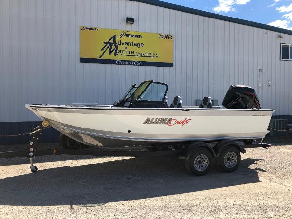 Slide: The Image of 2024 Alumacraft Trophy 195 boat on a trailer outside a marine dealership. - 1