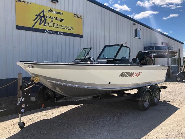 Slide: The Image of 2024 Alumacraft Trophy 195 boat on a trailer outside a marine dealership. - 2