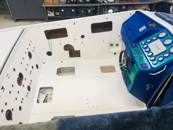 Slide: The Image of 1991 Apache POKER RUN CUSTOM boat interior with blue dashboard in a workshop. - 27