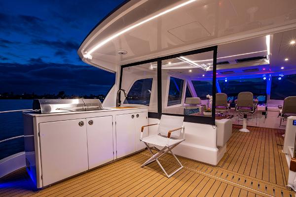 Slide: The Image of 2023 Aquila 70 Luxury yacht deck with outdoor kitchen and seating at dusk. - 10