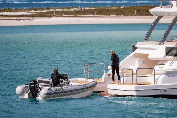 Slide: The Image of 2023 Aquila 70 Luxury yacht with a small boat in turquoise waters. - 7