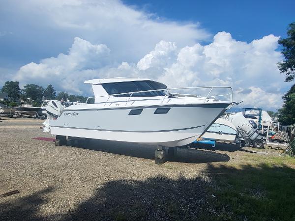 Slide: The Image of 2024 ArrowCat 320 boat on land with a cloudy sky background. - 0