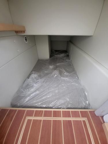 Slide: The Image of 2024 ArrowCat 320 interior cabin with plastic-covered bed and wooden flooring. - 8
