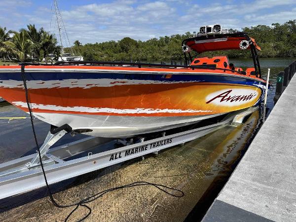 Slide: The Image of 2008 Avanti 36 boat on trailer at dock, vibrant orange and white design. - 1