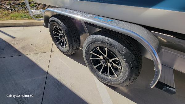 Slide: The Image of Dual axle wheels of 2024 Avenger AV26 boat trailer in sunlight. - 26