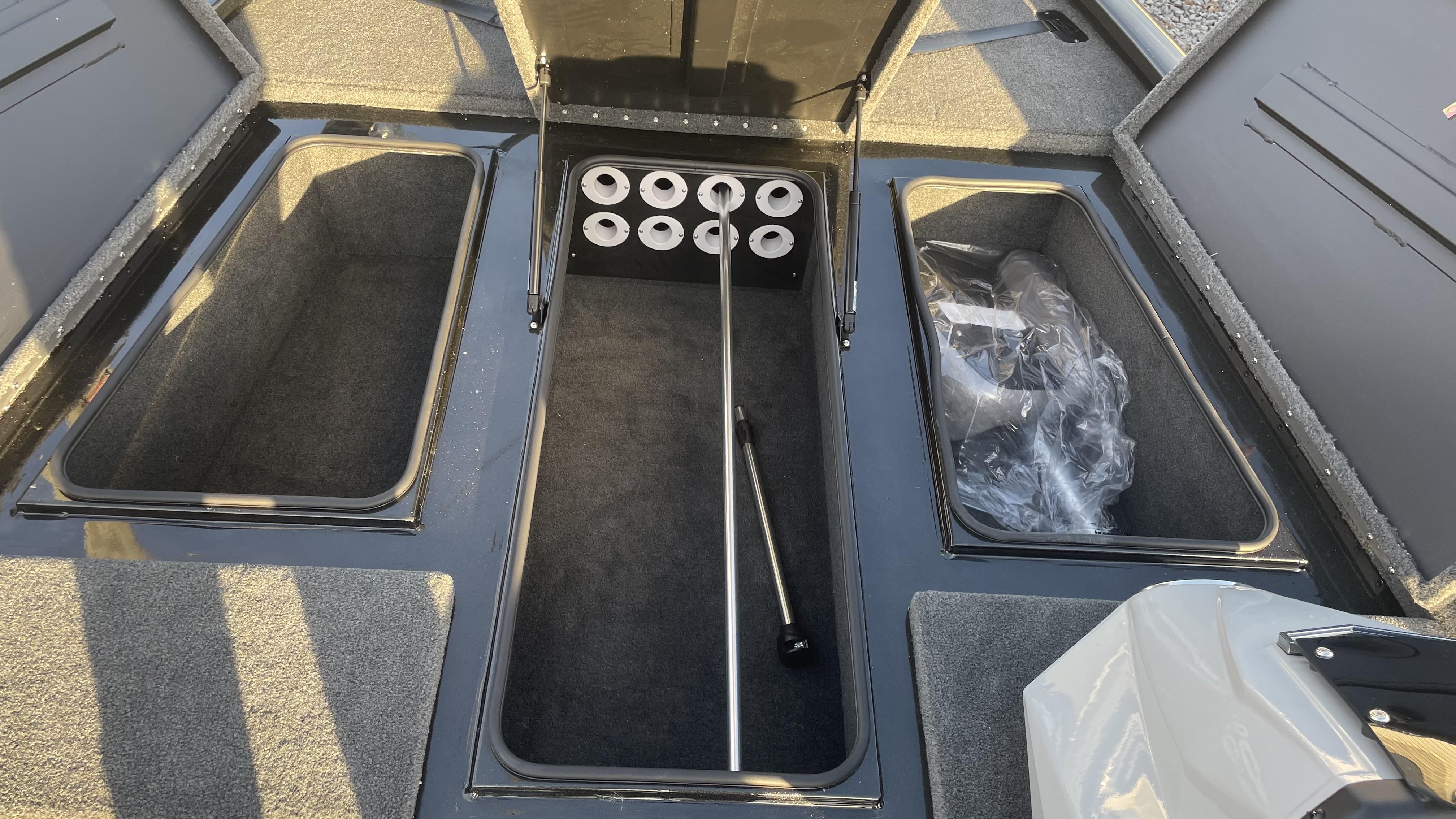 Slide: The Image of 2023 Avid 19XB boat storage compartments with rod holders and carpeted interior. - 12