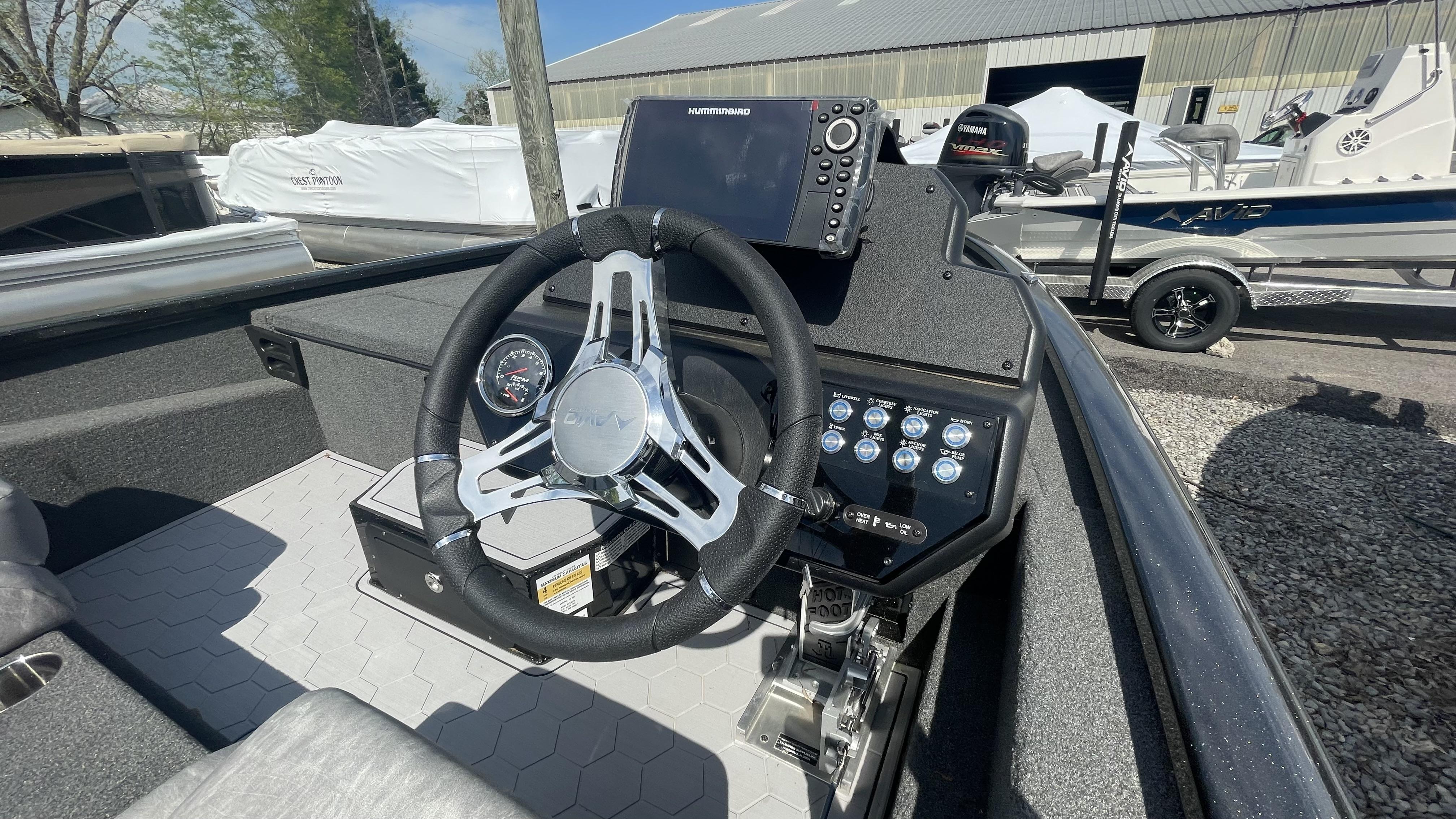 Slide: The Image of 2023 Avid 19XB boat dashboard with steering wheel, control panel, and Humminbird fish finder. - 7