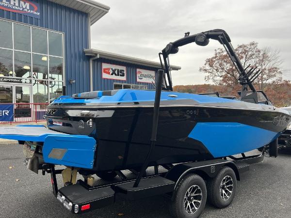 Slide: The Image of 2024 Axis A225 boat in blue and black on a trailer outside a dealership. - 10