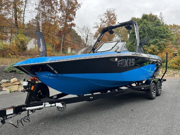 Slide: The Image of 2024 Axis A225 boat on a trailer, blue and black, parked outdoors. - 7