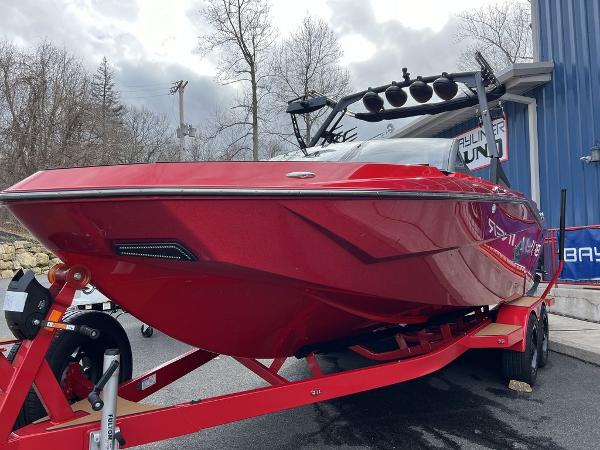 Slide: The Image of 2024 Axis T235 red boat on trailer outside showroom. - 2