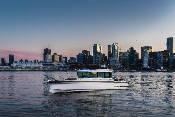 Slide: The Image of 2024 Axopar 37 Cross Cabin XC boat cruising near a city skyline at sunset. - 1
