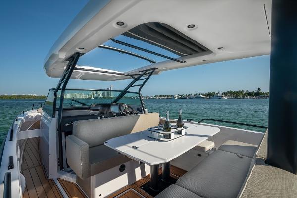 Slide: The Image of 2023 Axopar 37 Sun-Top boat interior with seating and table on the water. - 1