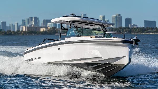 Slide: The Image of 2023 Axopar 37 Sun-Top cruising on water with city skyline in background. - 3