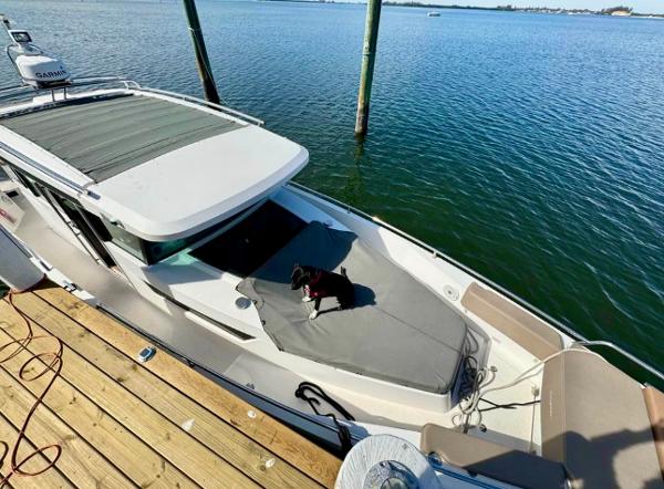 Slide: The Image of Axopar 37XC CROSS CABIN 2018 docked with a dog on the deck, overlooking calm waters. - 1