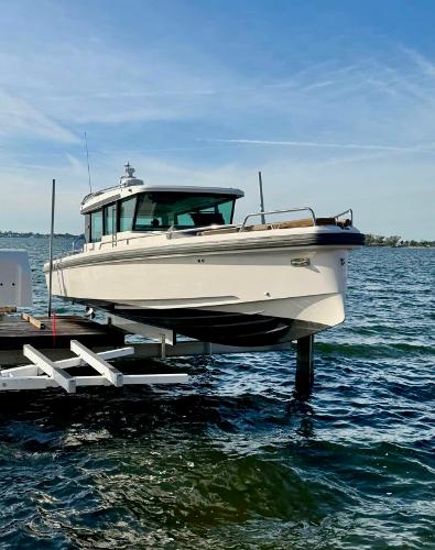 Slide: The Image of 2018 Axopar 37XC CROSS CABIN boat docked on a lift over water. - 2