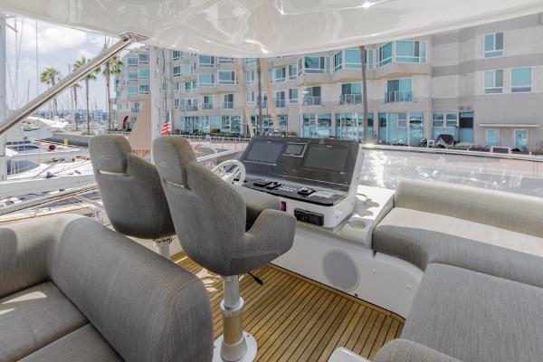 Slide: The Image of Azimut 60 Flybridge 2021 yacht helm with modern controls and seating, docked at marina. - 27
