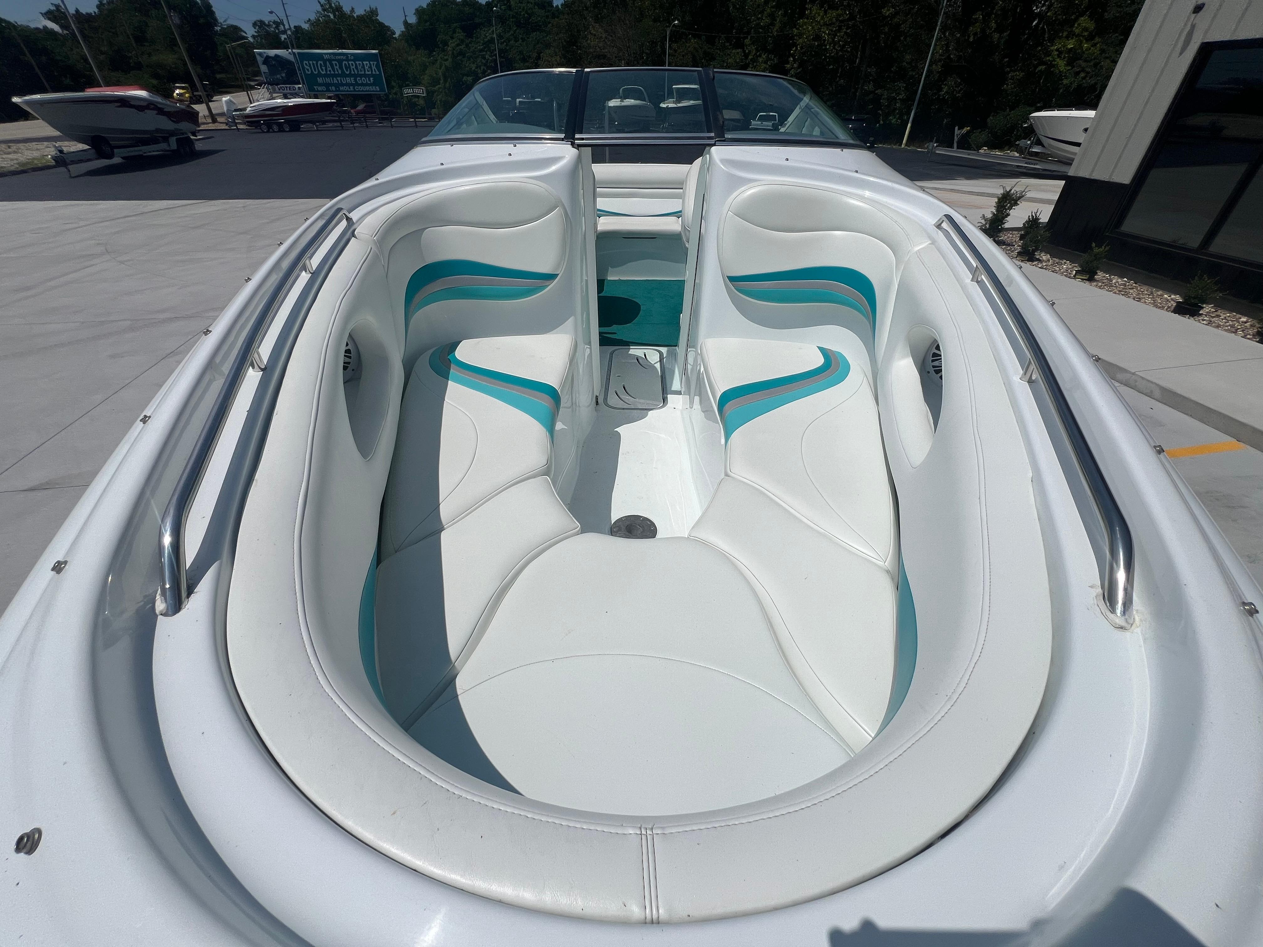 Slide: The Image of 1999 Baja 272 Islander boat interior with white and teal seating, docked outdoors. - 11