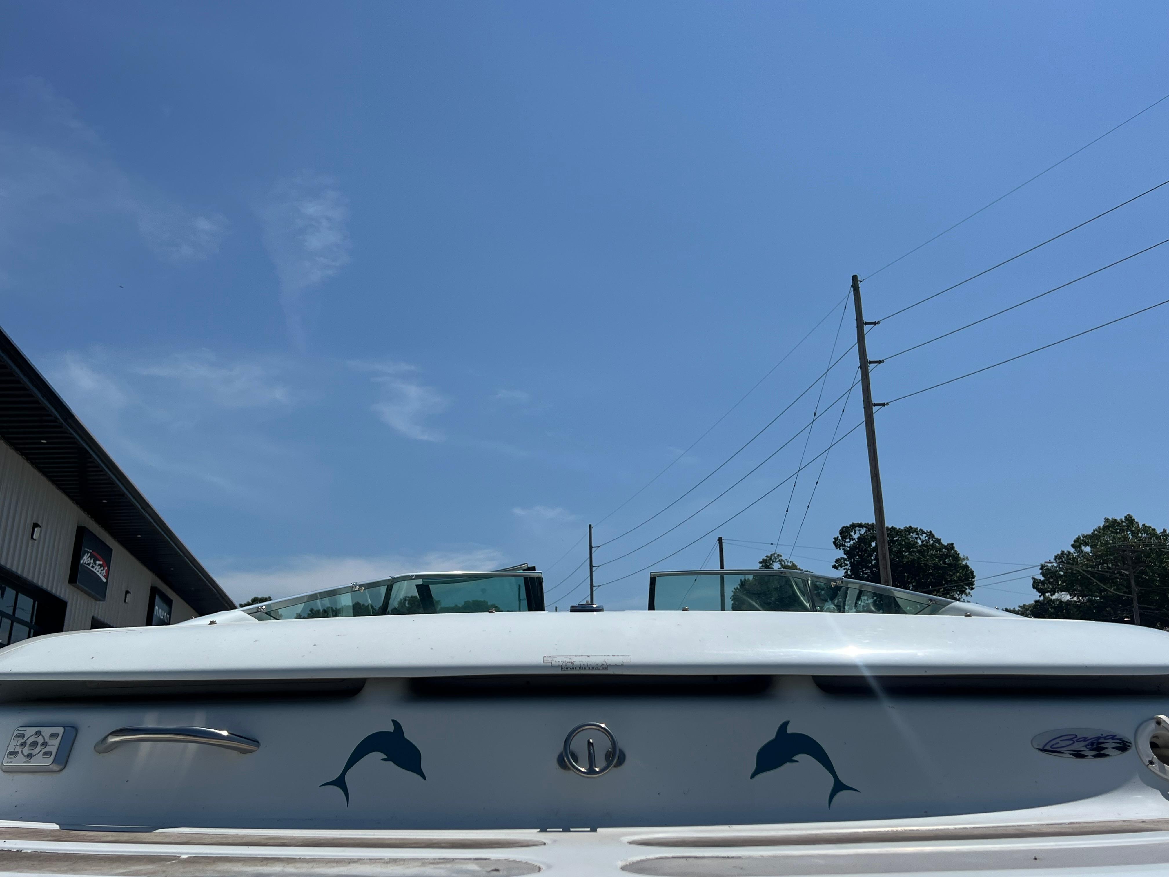 Slide: The Image of 1999 Baja 272 Islander boat with dolphin decals under a clear blue sky. - 14