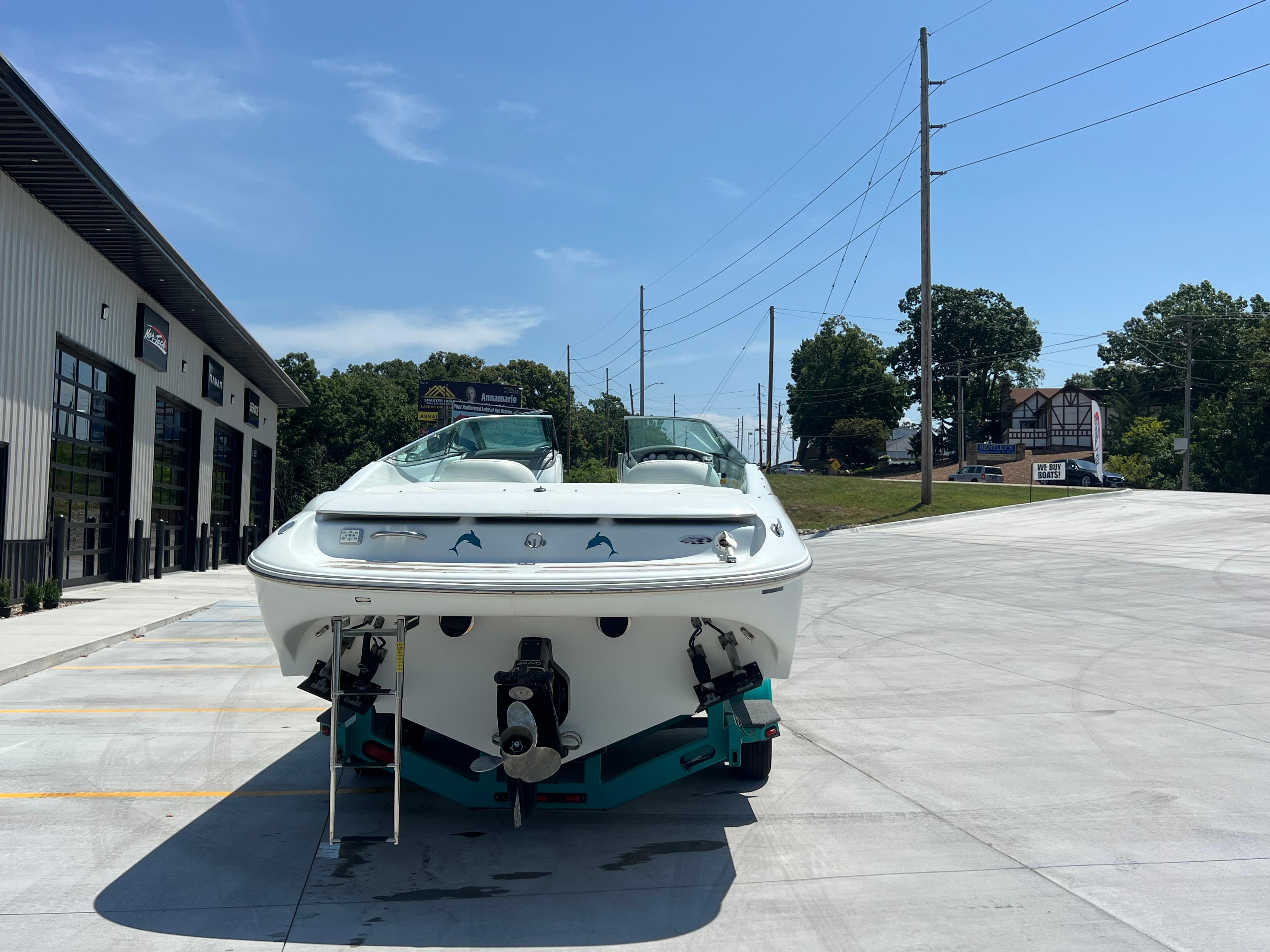 Slide: The Image of 1999 Baja 272 Islander boat parked outside a modern building under a clear blue sky. - 5