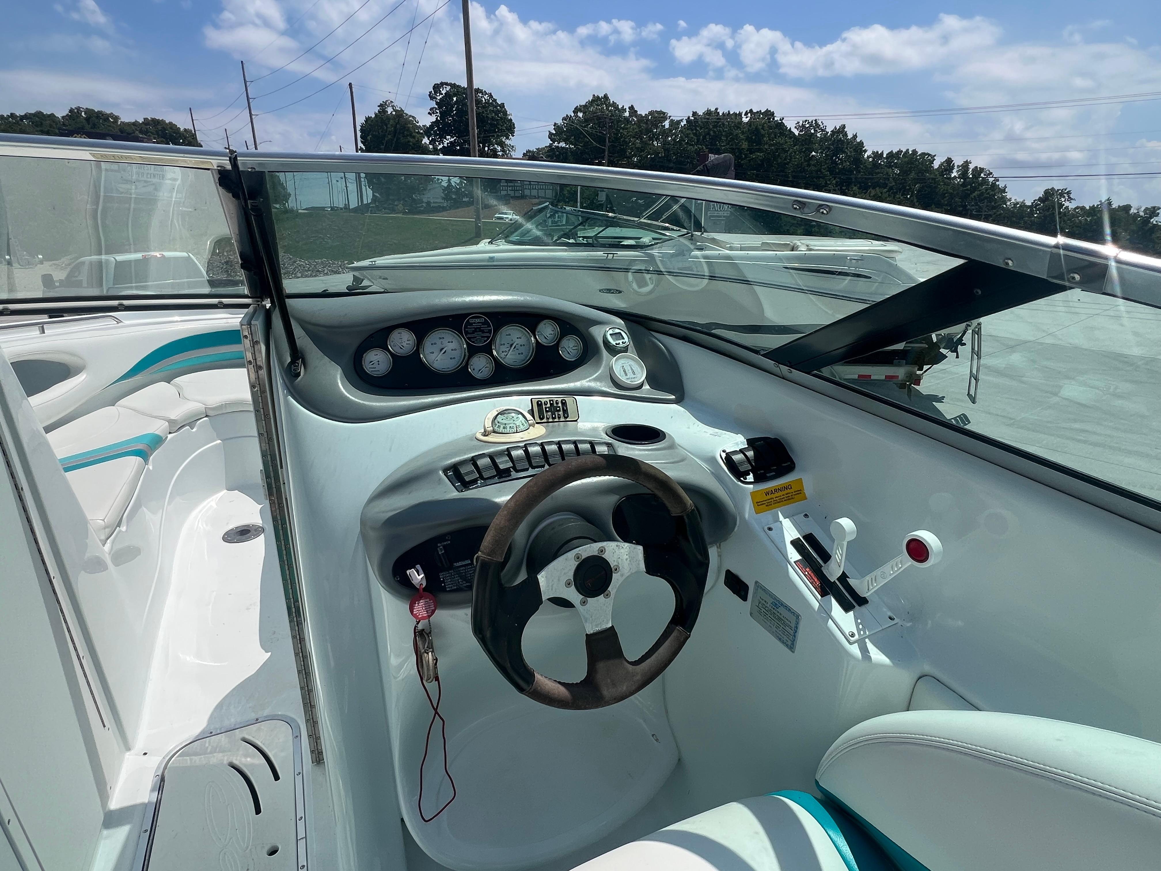 Slide: The Image of 1999 Baja 272 Islander boat cockpit with steering wheel and instrument panel under clear sky. - 8