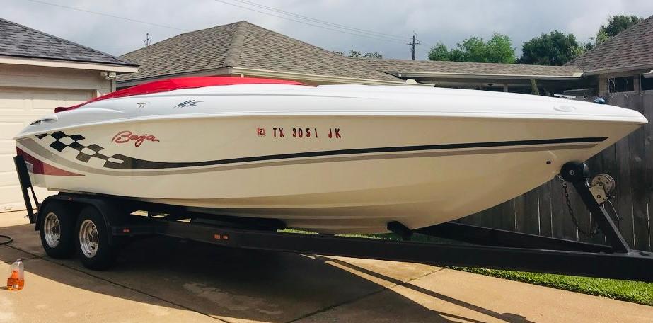 Slide: The Image of 2000 Baja H2X speedboat on trailer, white with red accents, parked in driveway. - 0
