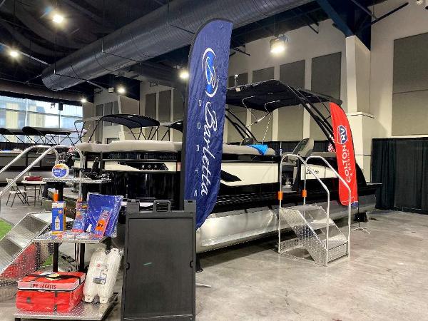 Slide: The Image of 2024 Barletta Corsa Ultra-Lounge 25UCA pontoon boat on display at an indoor boat show. - 2