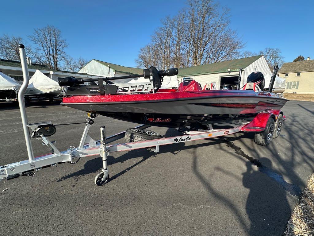 Slide: The Image of 2024 Bass Cat Boats Caracal STS on trailer, red and black, parked outdoors. - 1