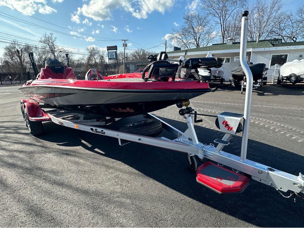 Slide: The Image of 2024 Bass Cat Boats Caracal STS on trailer, red and black, parked outdoors. - 11