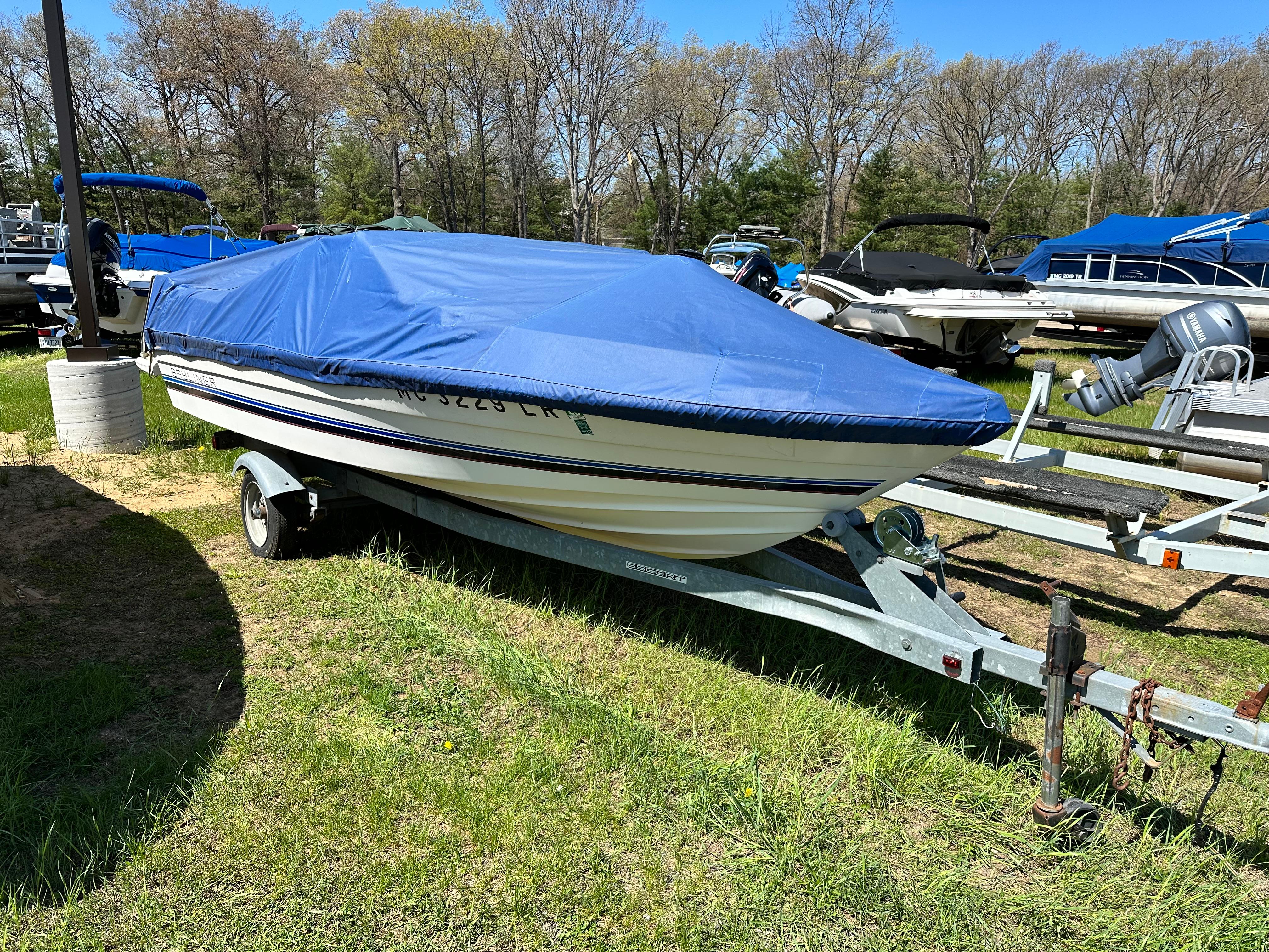 Slide: The Image of 1984 Bayliner Open Bow boat with blue cover on trailer in outdoor storage. - 1