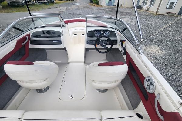 Slide: The Image of 2018 Bayliner 185 Bowrider interior with white and red seating, dashboard, and steering wheel. - 0