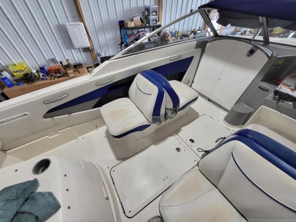 Slide: The Image of 2006 Bayliner 192 Discovery boat interior with white and blue seating in a garage setting. - 12