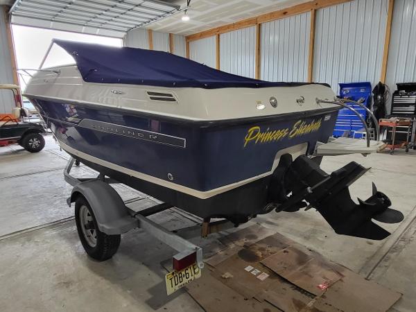 Slide: The Image of 2006 Bayliner 192 Discovery boat with blue cover on trailer in garage. - 6