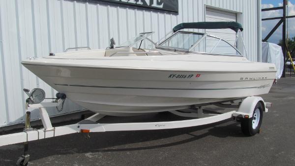 Slide: The Image of 2000 Bayliner 1950 Capri DX boat on trailer, parked outside a building. - 0