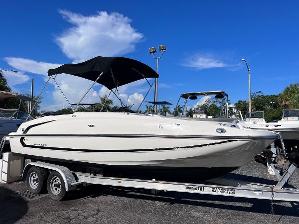 Slide: The Image of 2018 Bayliner 210 Deck Boat on trailer under clear blue sky. - 0