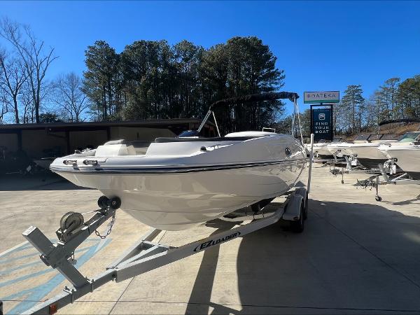 Slide: The Image of 2018 Bayliner 210 Deck Boat on trailer in sunny outdoor setting. - 0