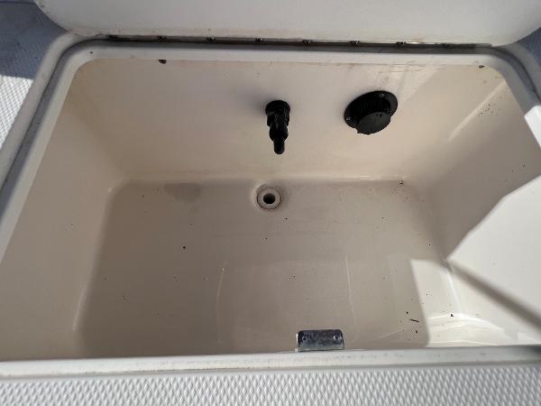 Slide: The Image of 2018 Bayliner 210 Deck Boat storage compartment with drain and fittings. - 16
