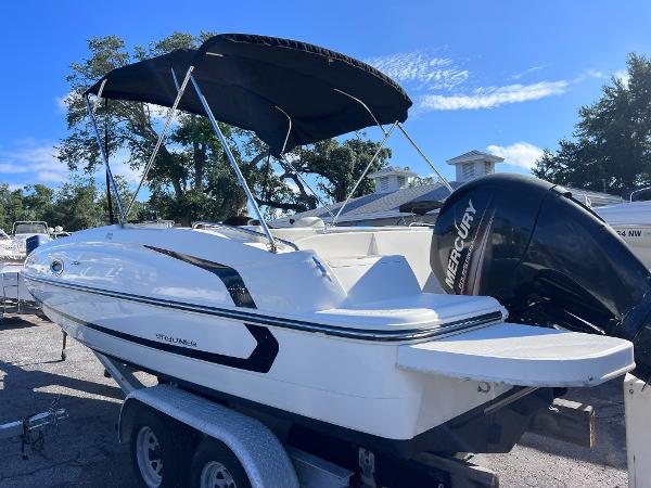 Slide: The Image of 2018 Bayliner 210 Deck Boat with Mercury outboard engine on trailer. - 2