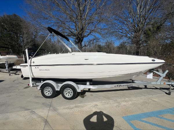 Slide: The Image of 2018 Bayliner 210 Deck Boat on trailer, parked outdoors. - 4
