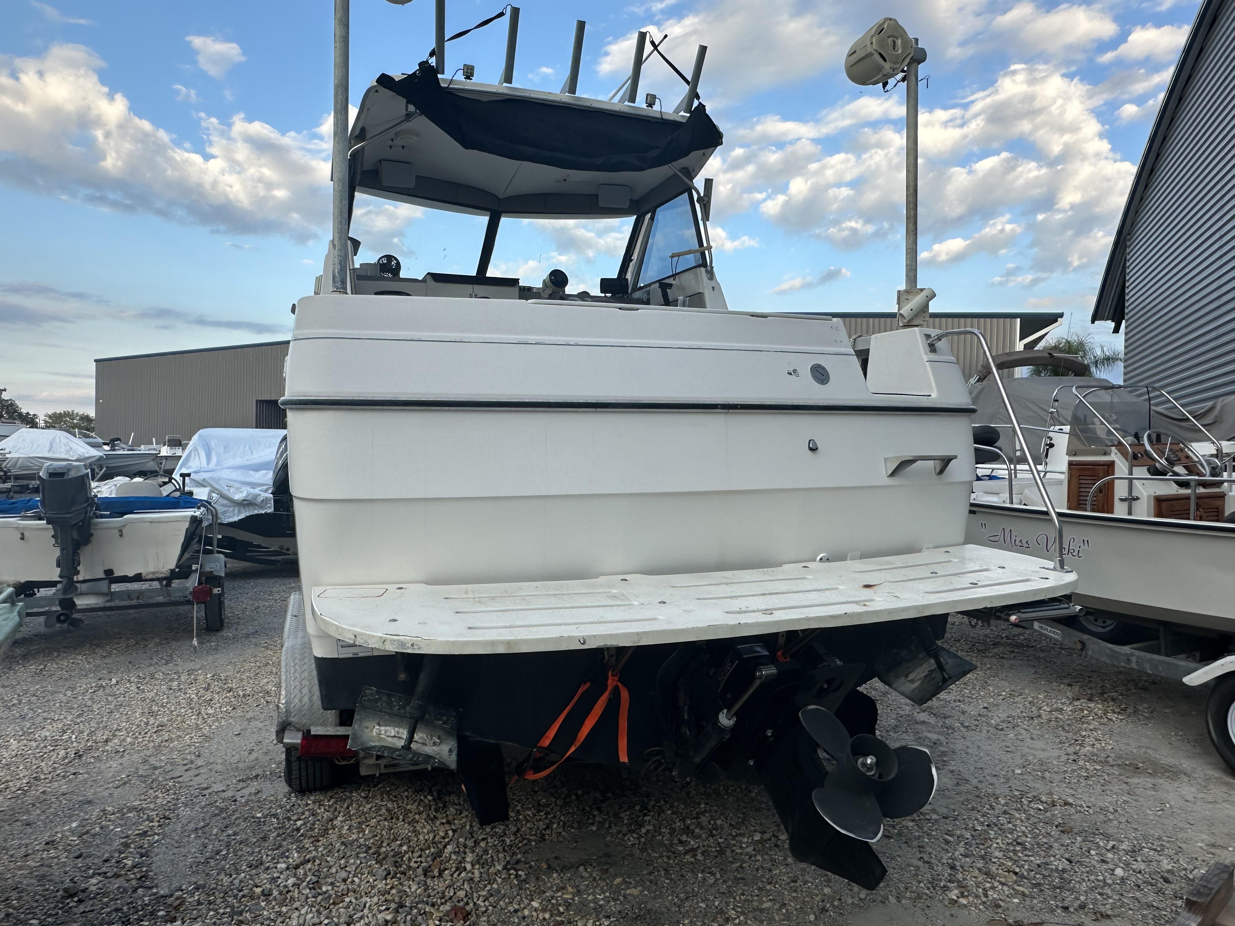 Slide: The Image of 1998 Bayliner 2452 Ciera Express boat, rear view, in a marina setting. - 13