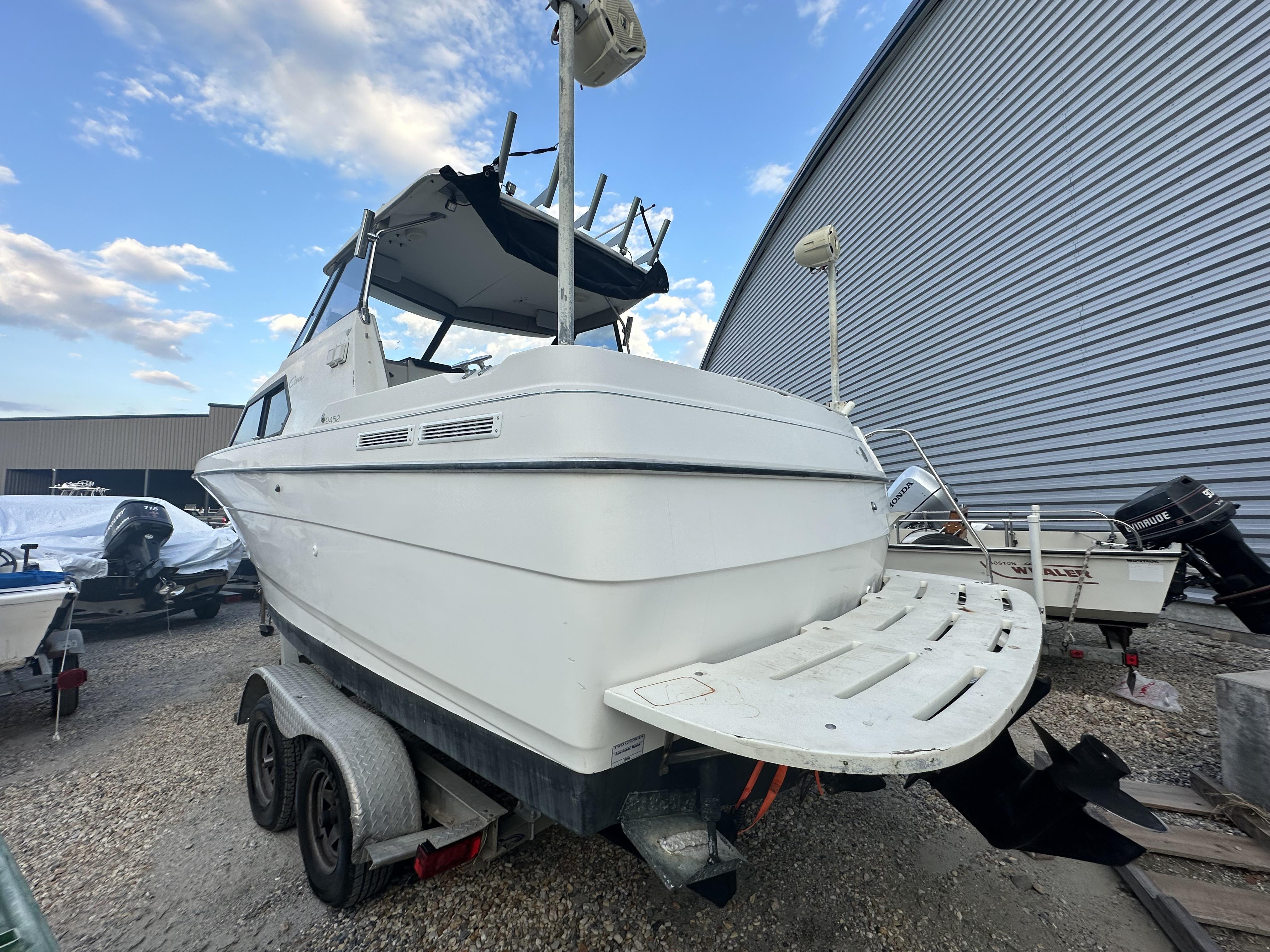 Slide: The Image of 1998 Bayliner 2452 Ciera Express boat on trailer, parked outdoors near a metal building. - 14