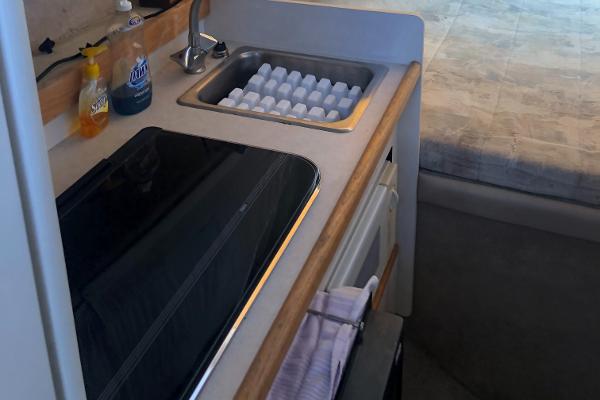 Slide: The Image of Compact kitchen area in a 1998 Bayliner 2452 Ciera Express boat with sink and stove. - 18