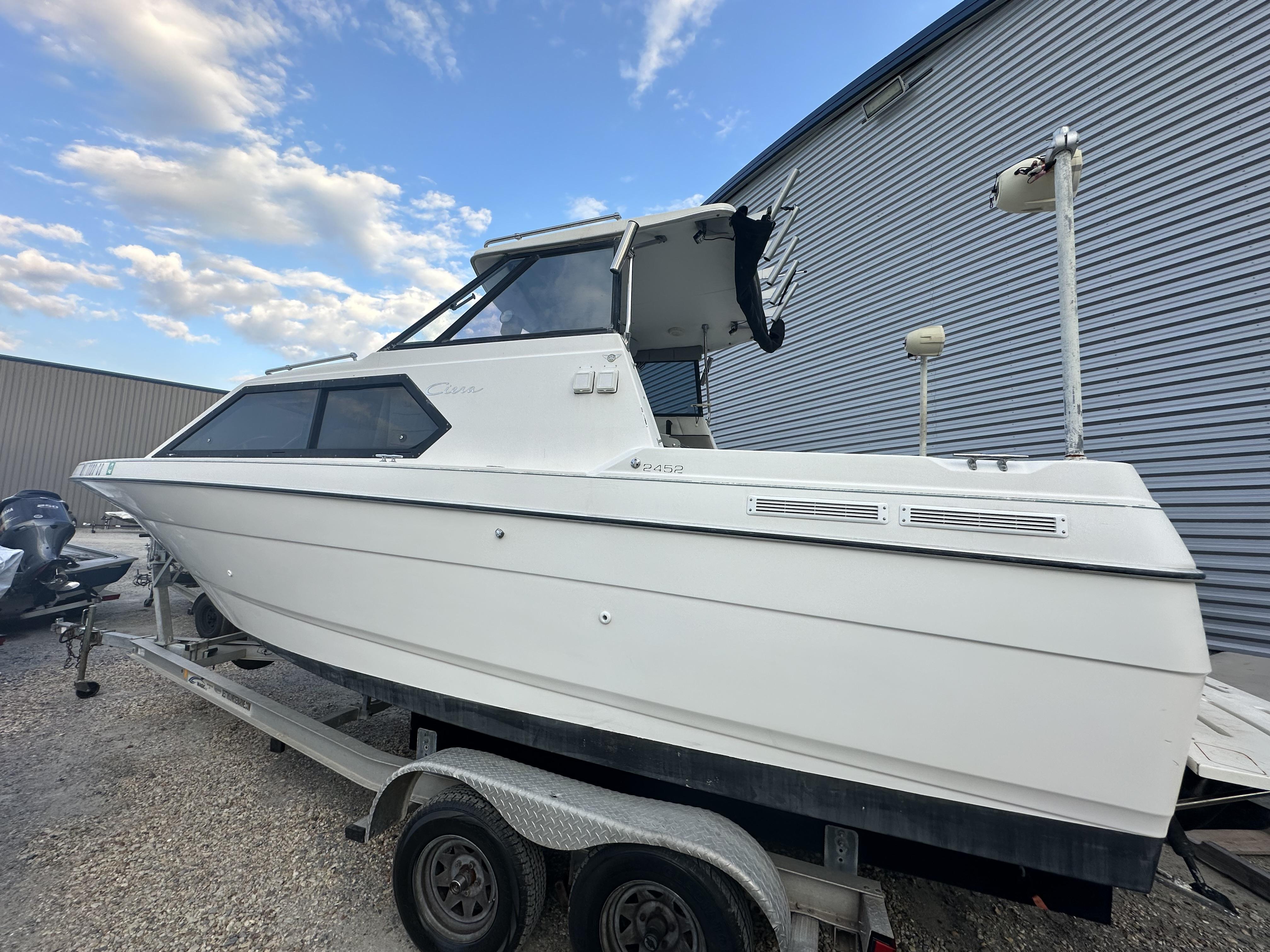 Slide: The Image of 1998 Bayliner 2452 Ciera Express boat on trailer, parked outdoors under blue sky. - 6