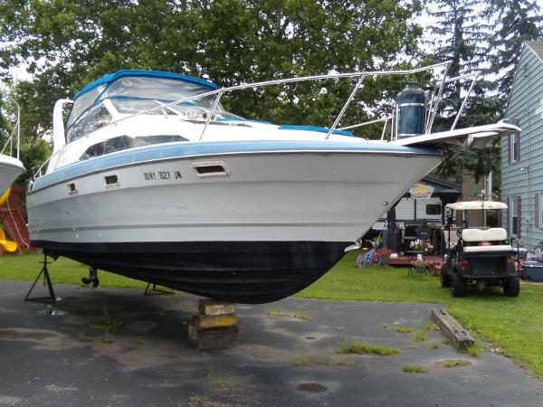Slide: The Image of 1988 Bayliner 2655 Ciera Sunbridge boat on land, blue canopy, parked near trees. - 1