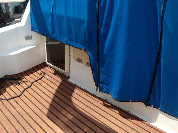 Slide: The Image of 1988 Bayliner 2655 Ciera Sunbridge deck with blue canvas cover and wooden flooring. - 15