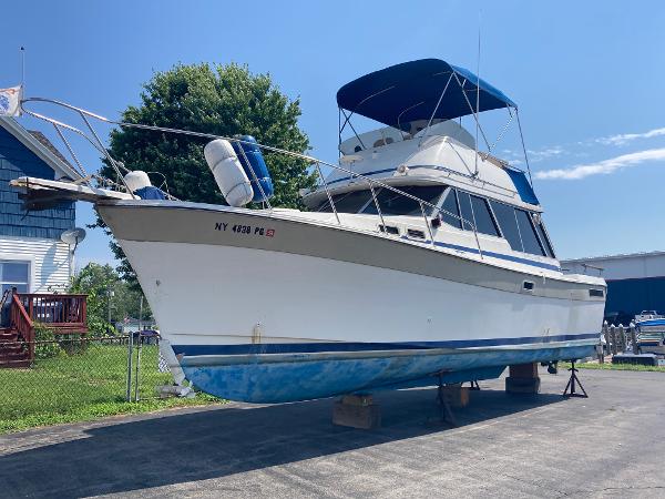 Slide: The Image of 1984 Bayliner 3270 Command Bridge boat on dry dock with blue canopy. - 0