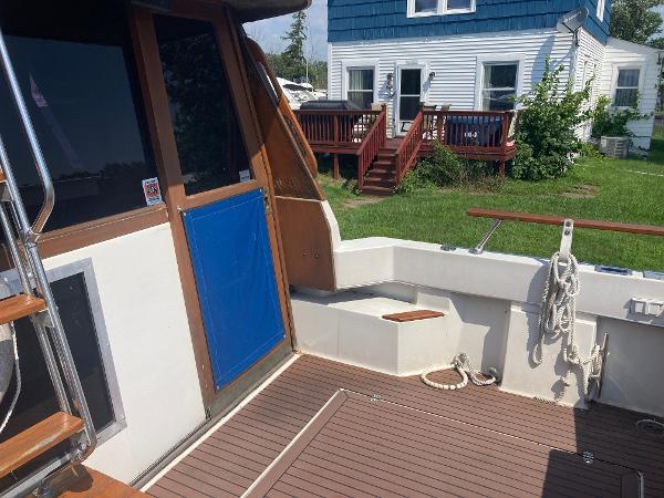 Slide: The Image of 1984 Bayliner 3270 Command Bridge boat deck with wooden steps and blue door. - 4