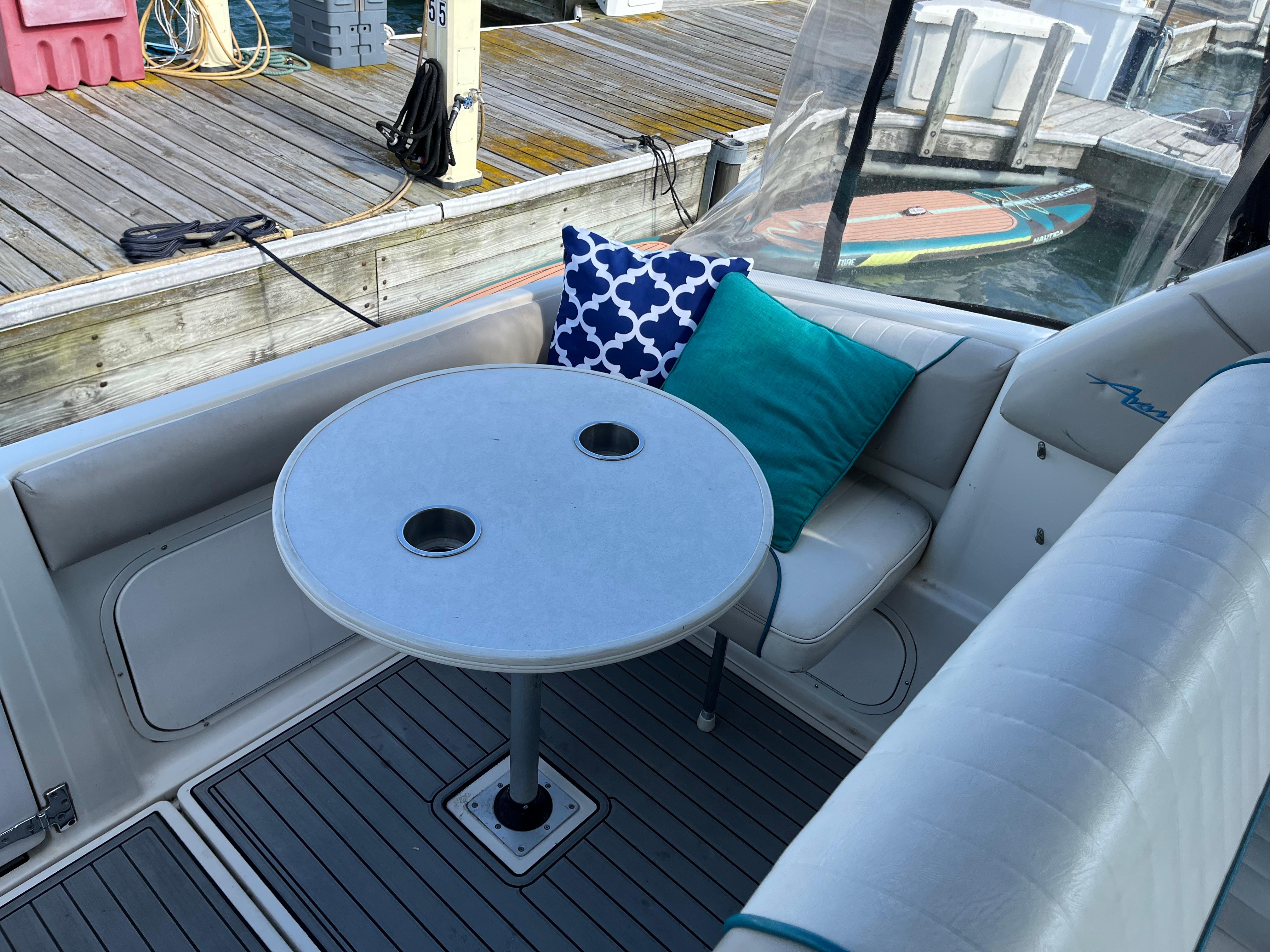 Slide: The Image of Bayliner 32 Avante 1996 boat interior with table, cushions, and dock view. - 17